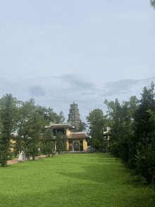 a large building with a tower in the background is surrounded by trees and grass