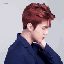 a man with red hair is wearing a blue suit and looking down .
