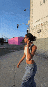 a woman is walking down a street in front of a building that says katseye