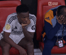 a soccer player sits in a stadium with a ziggo sport advertisement