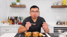 a man is eating a sandwich with a fork in a kitchen that says fortune animatical on the bottom