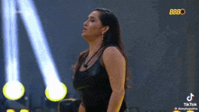 a woman in a black tank top is standing on a stage in front of a spotlight .