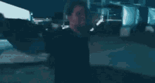 a man in a black shirt is standing in a dark room with a red light on his neck .