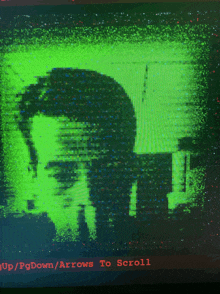 a green screen with a picture of a man and the words " up / pgdown / arrows to scroll " in red