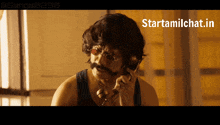 a man with a mustache and glasses is talking on a phone with a starttamilchat.in watermark