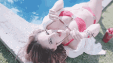 a woman in a red bikini is laying on the grass
