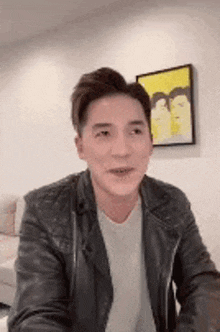 a man wearing a leather jacket and a white shirt is sitting in front of a couch .