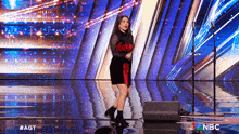 a woman in a red dress is standing on a stage in front of a microphone .