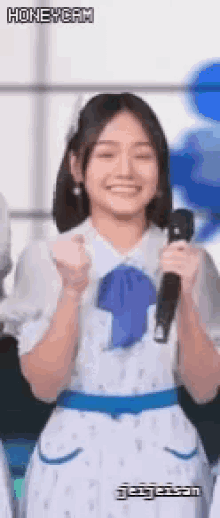 a woman in a white dress is holding a microphone in her hand and smiling .