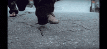 a close up of a person 's feet walking on a crack in the sidewalk .