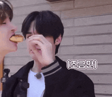 a man covering his face with his hand while another man feeds him