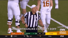 a referee is standing on a football field with a group of football players behind him .