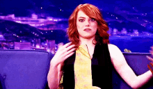 a woman with red hair is sitting on a couch and talking to someone .