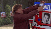 a man is hanging a sign on a tree that says for