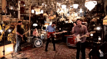 a group of men are playing guitars in a room with a leaf on the drum set