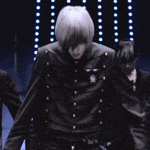 a man with a wig on stands in front of a group of people