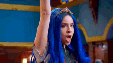 a woman with blue hair and a tiara on her head is standing with her arms in the air .