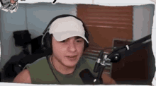 a man wearing headphones and a white hat is sitting in front of a microphone .