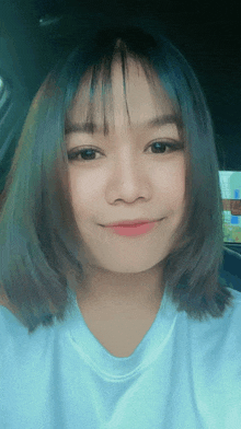 a girl with short hair and bangs is smiling and wearing a white shirt