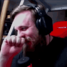 a man with a beard is wearing headphones and covering his face .