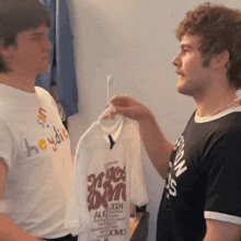 two men are looking at a t-shirt that says aug 2014