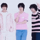three young men are standing next to each other and one is wearing a pink shirt that says frankie