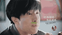 a man is eating a kfc sandwich with a green sticker on his nose .