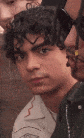 a man with curly hair looks at the camera