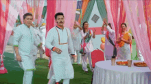 a group of people are dancing in front of a table .