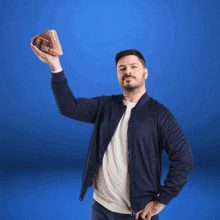 a man in a blue jacket is holding a piece of meat