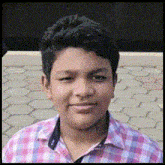 a young man wearing a plaid shirt is smiling for the camera