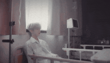 a man is sitting in a hospital bed with an iv in his arm