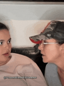 a woman wearing glasses and a baseball cap talks to a young girl