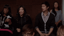 a group of people are sitting in a room and one of them is wearing glasses