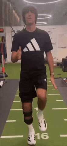 a man in a black adidas shirt is running on a track