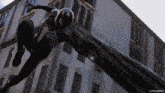 venom is flying through the air in front of a building .