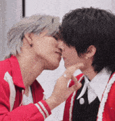 a man in a red jacket is kissing another man in a black shirt