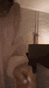 a person in a white shirt is standing in a room with a brick wall