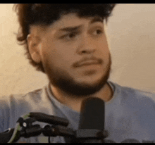 a man with a beard is standing in front of a microphone and making a face .