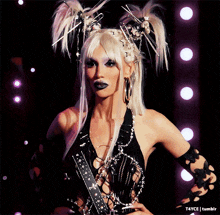 a woman with blonde hair and black makeup is standing in front of a bunch of lights and says tumblr on the bottom