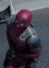a close up of a person in a deadpool costume standing on a sidewalk .