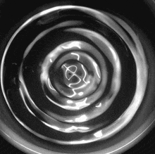 a black and white photo of a swirl in the water