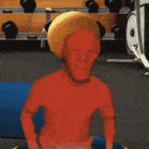 a red man with a yellow hat is sitting on a blue mat in a gym