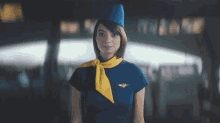 a stewardess wearing a blue hat and a yellow scarf looks at the camera