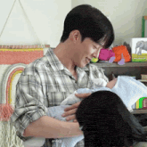 a man in a plaid shirt is holding a baby in his arms and smiling