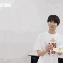 a man in a white shirt is holding a plate of food in his hands .