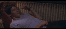 a man is laying on a striped couch with his mouth open