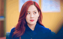 a woman with red hair is wearing a blue jacket and hoop earrings