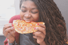 a woman is eating a slice of pizza with red nails