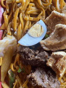 a close up of a plate of noodles with meat and an egg